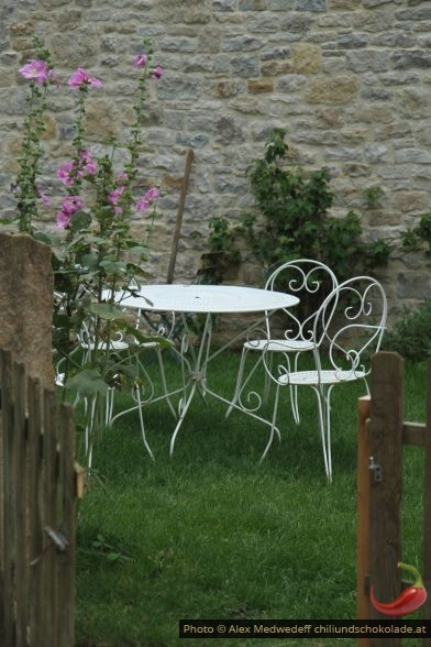 Table et chaises dans un petit jardin avec pelouse verte